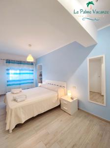 a white bedroom with a large bed and a mirror at Le Palme Vacanze in Trappeto