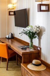 a vase of flowers on a desk with a vase of flowers at Dworek Morski SPA & Wellness in Mielno