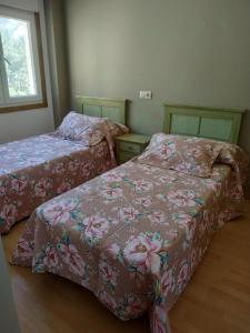 1 dormitorio con 2 camas y sábanas rosas con motivos florales en Nores Buenavista 2, en Vilaboa