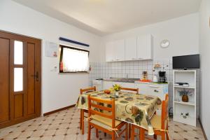 uma cozinha com mesa e cadeiras e uma cozinha com armários brancos em Apartments Mile 1249 em Fažana