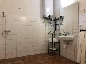 a white tiled bathroom with a sink and a shower at Penzion a hospoda Na statku in Hluboká nad Vltavou