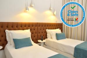 two beds in a hotel room with a sign that says clean and safe at Hotel Sol Algarve by Kavia in Faro