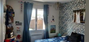 Schlafzimmer mit einem Bett und einem Fenster mit blauen Vorhängen in der Unterkunft Villa provençale climatisée avec piscine privée in Saint-Gilles