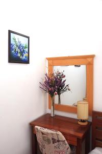 un jarrón de flores en una mesa de madera frente a un espejo en Dan Chi Hotel, en Da Lat