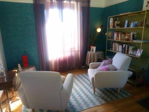 ein Wohnzimmer mit 2 Stühlen und einem Bücherregal in der Unterkunft vive les vacances in Plouguenast Langast