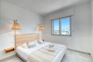 ein weißes Schlafzimmer mit einem Bett und einem Fenster in der Unterkunft Première ligne - Première conciergerie in Palavas-les-Flots