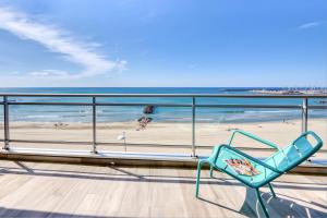a blue chair sitting on a balcony overlooking the beach at Première ligne - Première conciergerie in Palavas-les-Flots +2 photos