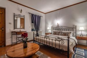 Un dormitorio con una cama y una mesa con un jarrón de flores en Beloi Hotel, en Vitsa