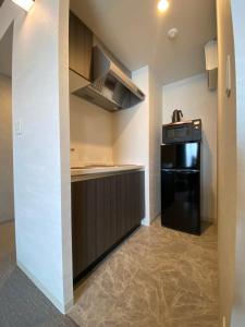 a kitchen with a black refrigerator and a stove at Randor Residential Hotel Fukuoka Classic in Fukuoka