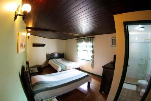 a small room with two beds and a shower at OYO Pousada do Wagner, Rio das Ostras in Rio das Ostras
