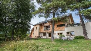 uma mulher sentada numa cadeira em frente a uma casa em Maison d'hôtes Agathe et Sophie em Lans-en-Vercors