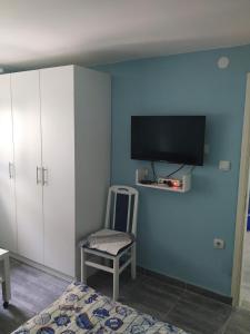 a bedroom with a blue wall with a tv and a chair at Apartman Azzuro Vrnjačka Banja in Vrnjačka Banja