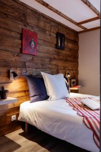 a bedroom with a white bed with a wooden wall at Echo des montagnes in Chalmazel Jeansagniere