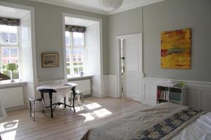 1 dormitorio con cama, mesa y ventanas en Vemmetofte Præstegård, en Faxe