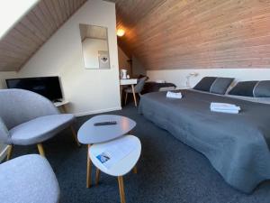 a bedroom with a bed and chairs and a television at Skagen Motel in Skagen