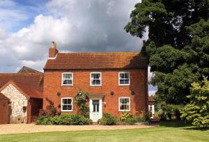 a large red brick house with a white door at Hawthorn Cottage at Waingrove Farm in Fulstow