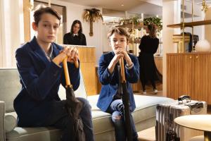 two young boys sitting on a couch holding umbrellas at Hôtel Gramont in Paris