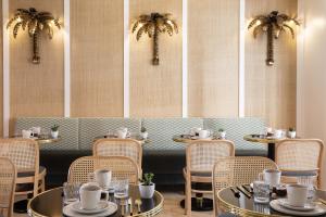 a restaurant with tables and chairs and palm trees at Hôtel Gramont in Paris