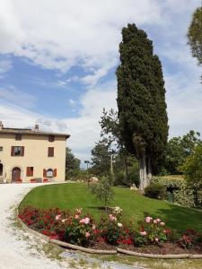 a garden with a tree and flowers in front of a building at Agriturismo VILLA MOZART nel verde in Gubbio
