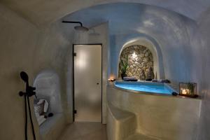 bagno con vasca e parete in pietra di Floria Suites a Karterados