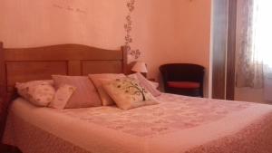 - une chambre dotée d'un lit avec des draps roses et une chaise dans l'établissement Chez Louis chambres d'hôtes à la ferme, à La Canourgue