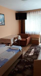 a bedroom with two beds and a couch and a television at Guest House Rusalka in Shipkovo