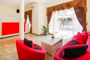 a living room with red chairs and a table at Super OYO 2771 D'soetta in Malang
