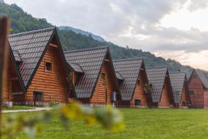 a row of wooden lodges in a field of grass at Rafting Center Drina Tara in Bastasi