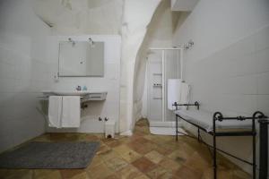 La salle de bains blanche est pourvue d'un lavabo et d'un miroir. dans l'établissement B&B Il Palazzotto del Caveoso, à Matera