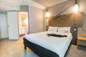 a bedroom with a large white bed and a bathroom at ibis Alger Aéroport in Alger