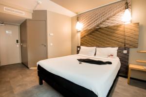 a bedroom with a large white bed with a wooden headboard at ibis Alger Aéroport in Alger