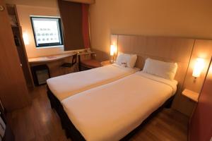 a bedroom with two beds and a desk and a window at ibis Alger Aéroport in Alger