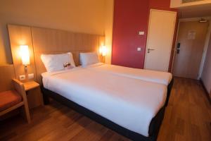 a large white bed in a room with a chair at ibis Alger Aéroport in Alger