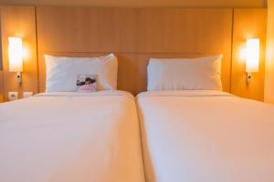 two beds in a hotel room with white sheets at ibis Alger Aéroport in Alger