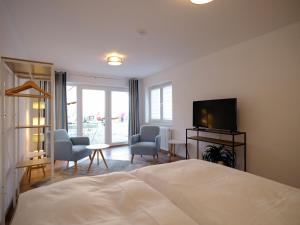 1 dormitorio con 1 cama, TV y sillas en Travel Art Boardinghouse en Neuruppin