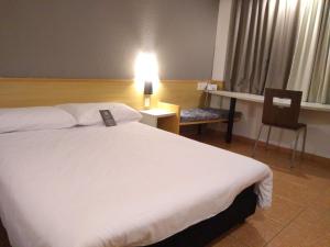 a hotel room with a large white bed and a chair at ibis Santos Gonzaga Praia in Santos