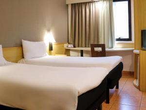 um quarto de hotel com duas camas e uma mesa em ibis Santos Gonzaga Praia em Santos