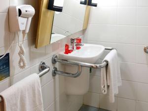 a bathroom with a sink and a mirror and towels at ibis Santos Gonzaga Praia in Santos