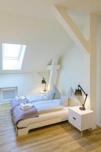 a white bedroom with a large bed and a window at Quartier36 in Schleswig