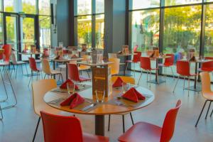 a dining room with tables and chairs and windows at ibis Alger Aéroport in Alger