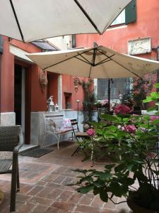 威尼斯的住宿－亨利的天堂公寓，一个带遮阳伞、椅子和鲜花的庭院