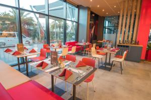 a restaurant with tables and chairs and windows at ibis Alger Aéroport in Alger