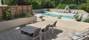 een patio met een tafel en stoelen naast een zwembad bij Les Prairies de l'Encrême in Céreste