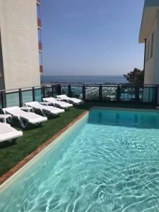 una piscina con tumbonas y sillas en un edificio en Hotel Mirage en Lido di Classe