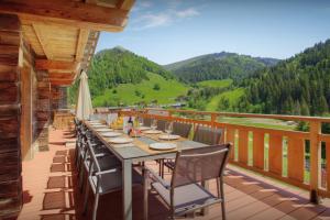 a dining table on a deck with a view of mountains at Chalet Goville - OVO Network in La Giettaz