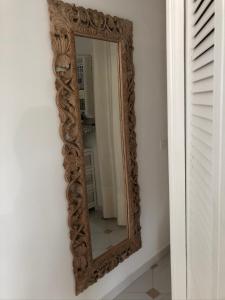 um espelho com uma moldura de madeira esculpida numa parede em Villa Oïa em Lorgues