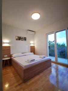a bedroom with a large bed and a large window at Apartments and Rooms Kod Mate in Tribanj-Krušćica