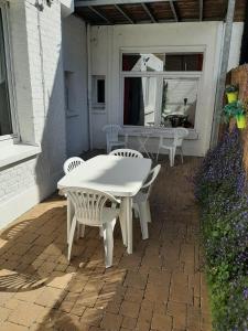 una mesa blanca y sillas en un patio en Le Rusticka, en De Panne