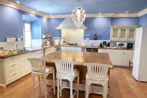 cocina con mesa de madera y sillas blancas en Villa Rural La Condesa, en Ronda