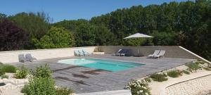 a swimming pool with two chairs and an umbrella at LES PRAIRIES DE L'ENCREME in Céreste